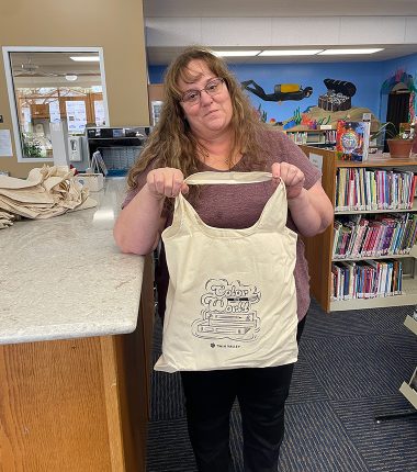 A librarian receives a bunch of “Color Our World” reading bags at the Minneapolis Public Library as part of the summer reading program.