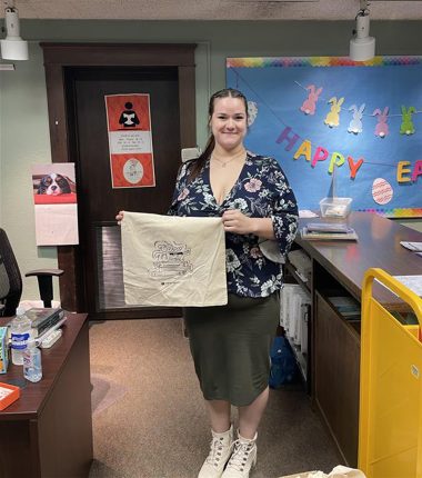 A librarian receives a bunch of “Color Our World” reading bags at the Clay Center Public Library as part of the summer reading program.