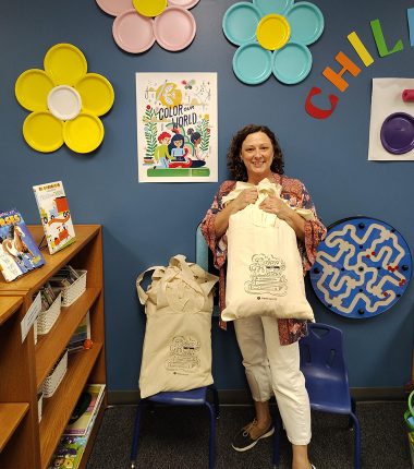 A librarian receives a bunch of “Color Our World” reading bags at the Belle Plaine Public Library as part of the summer reading program.